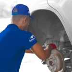 Technician in uniform working on a vehicle’s brake system, showcasing expert service and precision in Brake Repair Altamonte Springs at Ruben’s Tires.