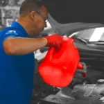Technician in blue uniform pouring oil into a vehicle engine, delivering professional and reliable Oil Change Altamonte Springs services at Ruben’s Tires.