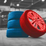 Stack of blue tires with a red performance wheel in a garage setting, visually highlighting professional Tire Repair Altamonte Springs services at Ruben’s Tires.