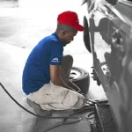 Ruben’s Tires technician in red cap and blue uniform performing air pressure check and tire maintenance, showcasing expert Tire Repair Altamonte Springs service.