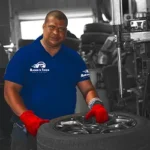 Ruben’s Tires technician handling a wheel inside the service bay, representing expert care and value with the Rubens Tires Tire Rotation Balance Offer.